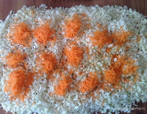 Нашинковать как можно мельче. По столу разложить толстеньким слоем. На него же морковь натереть. Сюда же соль, сахар, тмин, семена горчицы и укропа. Все руками хорошенько мешаем и давим, мешаем и давим... Чеснок — каждый зубчик вдоль пополам разрезали и сюда же. Кроме аромата и «крепости», что они привнесут в капустку — это самый точный индикатор готовности квашения, смотрите ниже.