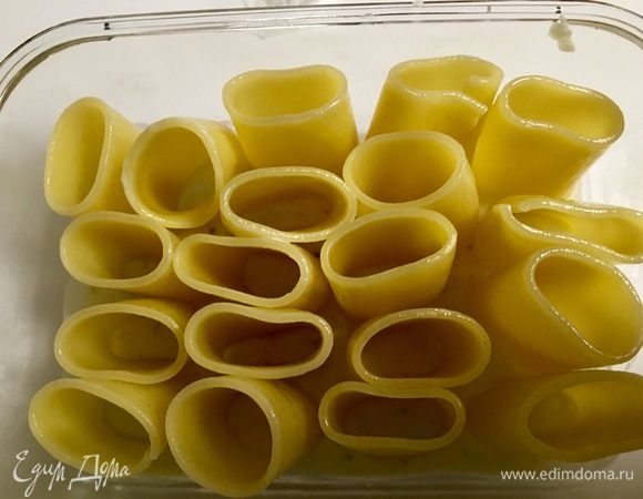 Взять форму, в которой будем запекать пасту. Дно формы покрыть соусом «бешамель». Вертикально поставить макарончики, приклеивая их как бы с помощью соуса ко дну формы.