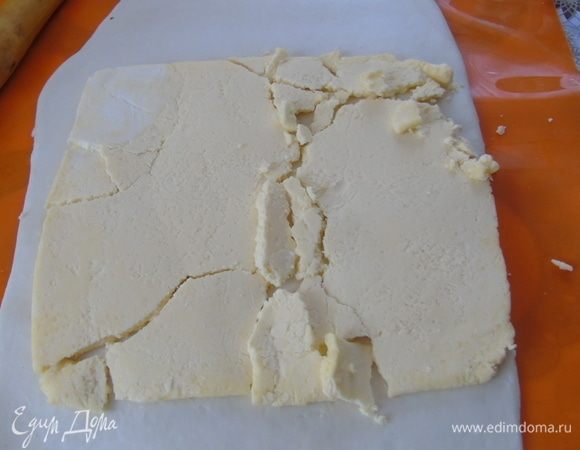 На следующий день тесто достаем из холодильника, слегка разминаем ладонью, раскатываем в пласт примерно 38*19 см. На середину выкладываем пласт масла. У меня масло домашнее и немного раскрошилось.