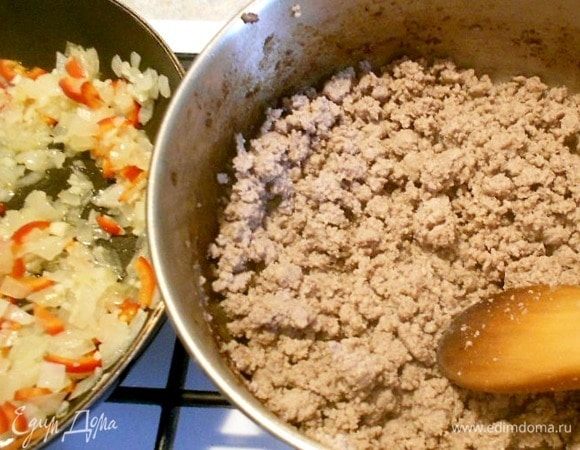 Одновременно в глубоком сотейнике на оставшемся масле обжарить фарш до коричневого цвета, постоянно разминая комки деревянной ложкой. Мясо должно именно поджариться и приобрести коричневатый цвет, а не быть тушеным. Огонь может быть средним или чуть больше.