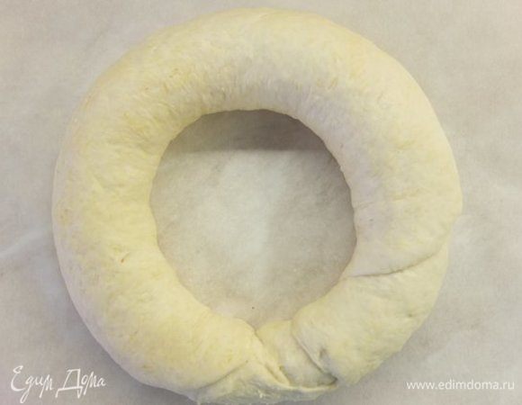 По широкой стороне сворачиваем тесто в рулет. Придаем форму бублика и выкладываем в круглую форму, застеленную пергаментом. 