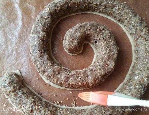 Так выложить смесь по всей спирали. Спираль у вас получится такой длины, на сколько хватит начинки. Высоту регулировать можно тоже по своему желанию. Подготовим будущий торт для выкладки теста, для этого кисточкой уберем все ореховые крошки.
