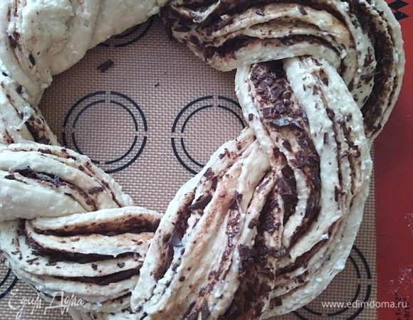 Переплести оба конца и соединить в венок. Духовку разогреть до 180°C. Смазать венок молоком и поставить выпекаться на 30 минут.