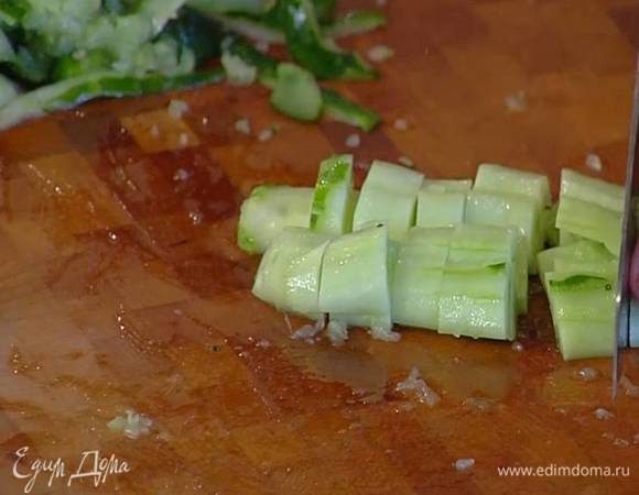 Огурцы, срезав кожуру, разрезать пополам и удалить семена, мякоть раздавить плоской стороной ножа, затем нарезать кусочками.