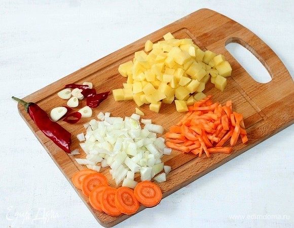 Подготовим овощи. Очищаем и нарезаем: картофель и лук — кубиками, морковь — соломкой, чеснок — слайсами, острый перец и сельдерей — дольками.
Картофель отвариваем в оставшейся воде.
