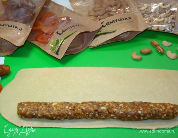 Часть теста тонко раскатать в прямоугольник. Из начинки сформировать колбаску и уложить вдоль с одного края. Завернуть в один оборот тесто и лишнюю часть отрезать.
Рулетик нарезать наискосок кусочками, длиной примерно 5 см.