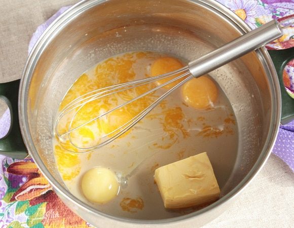 Добавить яичные куриные желтки (4 шт.) и масло сливочное (90 г) комнатной температуры. Тщательно перемешать, слегка взбивая венчиком.