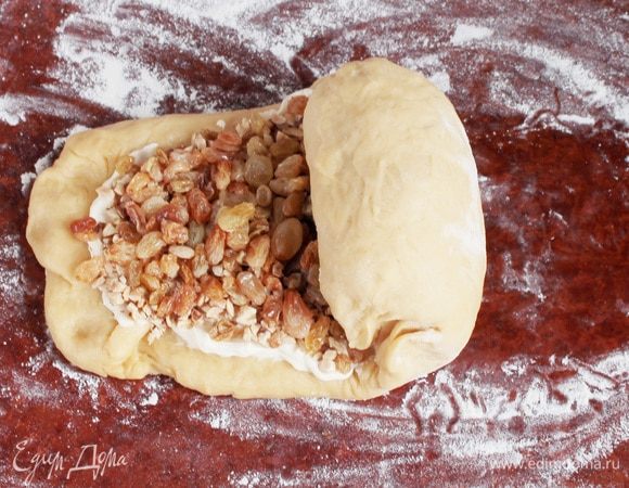 Сверху выложить подготовленный изюм и аккуратно ладонью придавить начинку к тесту. Свернуть рулет, сразу при сворачивании защепляя торцы. Аккуратно защипнуть край, а торцы подвернуть внутрь рулета.