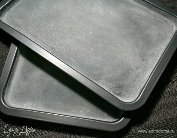 Идеально было бы взять 3 кольца для выпечки диаметром 16 см и испечь три одинаковых бисквита, но так как как у меня нет 3 колец, я поступила иначе: взяла 2 противня 22Х34 см (внутренний размер) и решила испечь 4 бисквита потоньше. Для этого смазала противни холодным сливочным маслом и посыпала их мукой, стряхнув остатки. Можно просто положить на противень бумагу для выпечки.