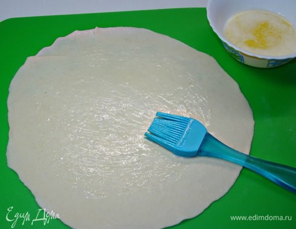 По рецепту необходимо каждый шарик, обильно посыпав смесью из муки и крахмала, раскатать в небольшой диаметр и, сложив стопочкой, раскатать в тонкие лепешки, которые потом разъединить. Но я не стала рисковать и каждую лепешку раскатывала по отдельности. Затем серединку смазать растопленным сливочным маслом и перевернуть смазанной стороной вниз.