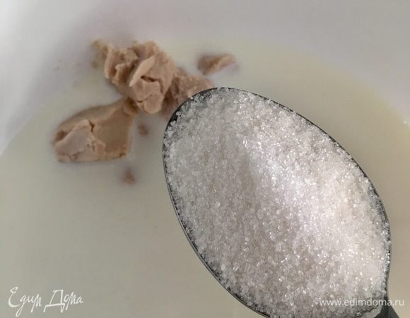 Сперва подогреть 300 мл молока до теплого состояния. В молоко раскрошить свежие дрожжи и всыпать одну столовую ложку сахара. Перемешать до растворения дрожжей, накрыть миску пищевой пленкой и оставить минут на 15, пока дрожжи не начнут работать.