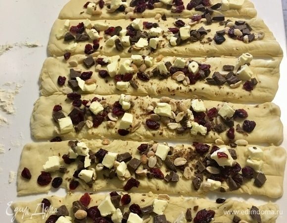 Выкладываем в хаотичном порядке начинку: орехи, клюкву, шоколад и холодное сливочное масло. Ножиком аккуратно разрезаем его на 6 полос.
