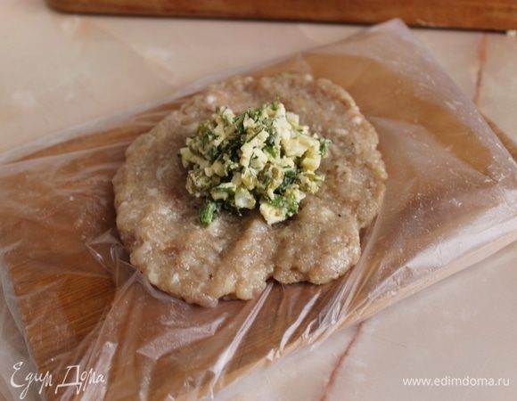 Разделите фарш на порции. На каждую порцию отмерьте примерно 50–70 граммов фарша. Влажными руками хорошо выбивая, из каждой порции фарша вначале делаем шарики, а потом расплющиваем их в лепешку. Положите столовую ложку начинки и заверните ее внутрь. Периодически смачивайте руки холодной водой, и фарш не будет прилипать к ним.