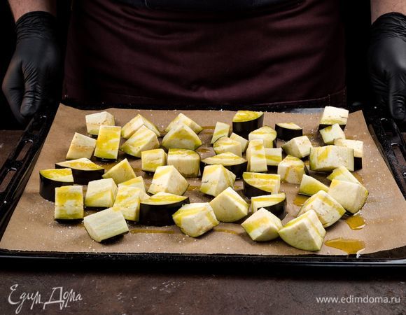 Баклажан нарежьте кубиками и выложите на застеленный пергаментом противень. Запеките в духовке приблизительно 15 минут до мягкости.