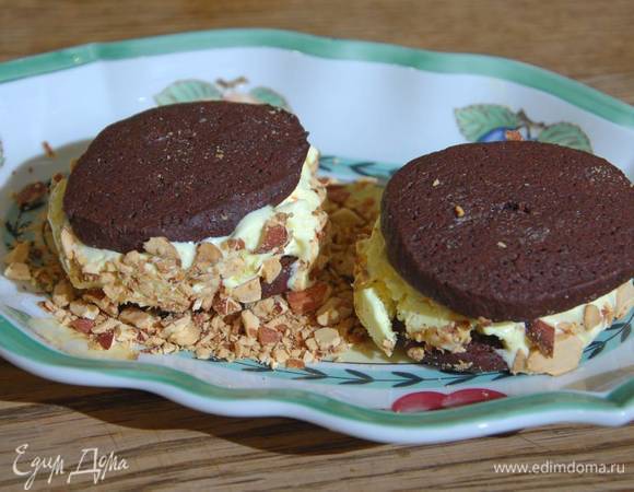 Готовое мороженое разложить на половину всего печенья, накрыть оставшимся печеньем, обсыпать получившиеся сэндвичи измельченным миндалем и отправить ненадолго в морозилку.