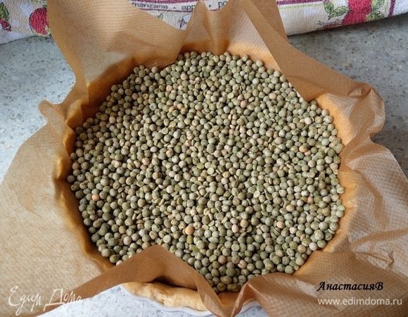 Сверху покрываем бумагой для запекания и высыпаем 500 граммов сухого гороха (или фасоли, у кого что есть). Запекаем в духовке на самой нижней полке 25 минут. Тесто запекается предварительно для того, чтобы держало форму. Использованный горох можно остудить и хранить в банке до следующего киша.
