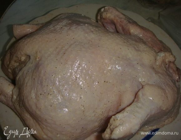 Дольки чеснока разрезать на 4 части и нашпиговать ими тушку. Обмазать курицу сметаной и оставить мариноваться на 20 минут.