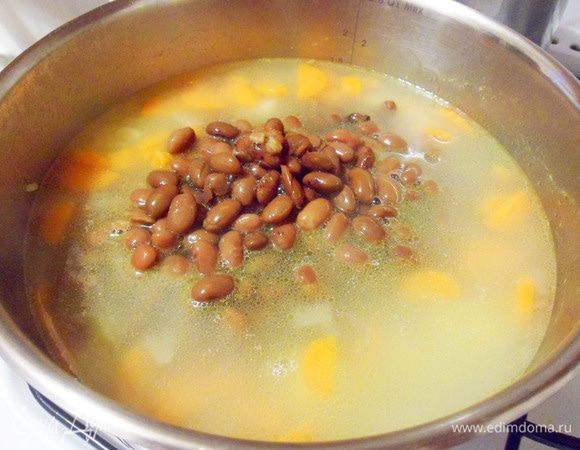 Добавить консервированную фасоль к готовым овощам в кастрюлю.