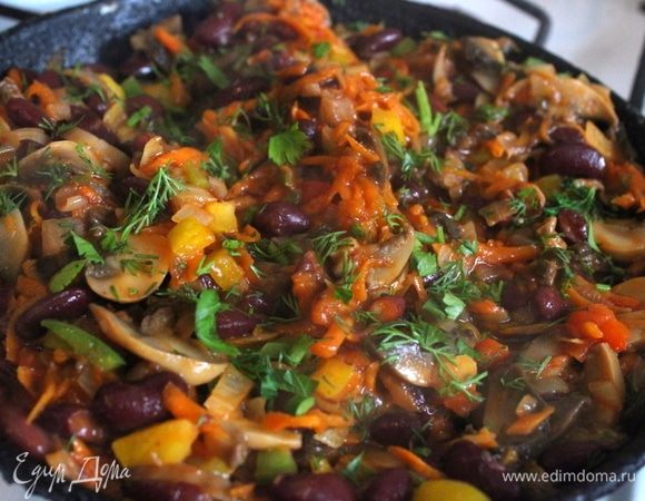 Добавляем к обжаренным продуктам зелень и томатную пасту, немного тушим. 