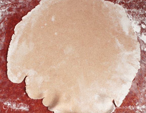 Аккуратно вытянуть «отдохнувшее» тесто в очень тонкий пласт на припыленной пшеничной мукой поверхности. Если не получается, то воспользуйтесь скалкой.