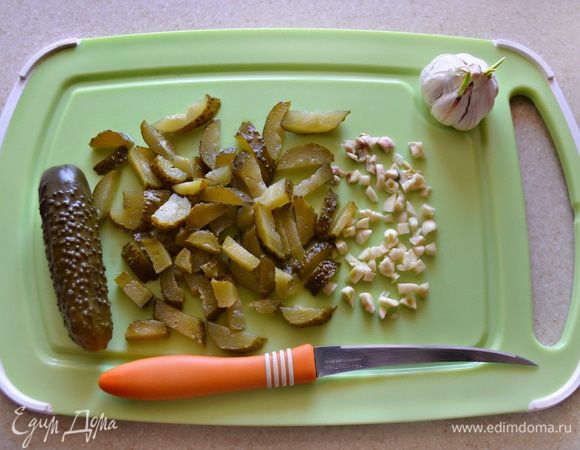 С соленых огурцов срезать «хвостики» и нарезать соломкой. Чеснок очистить и мелко порубить.