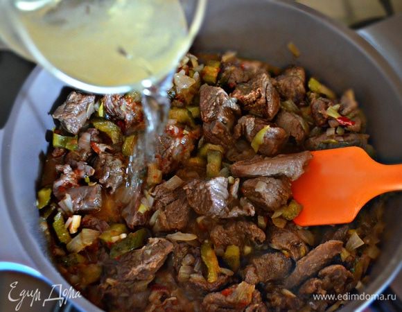 Влить вино и тушить под крышкой примерно 45 мин. При необходимости добавляйте горячую воду.