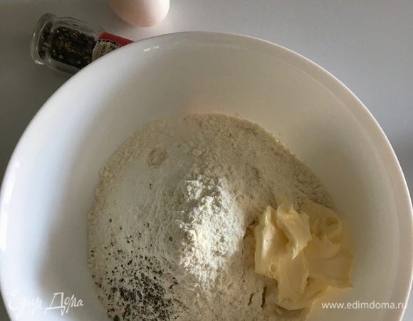 В большую чашу просеять муку с солью и свежемолотым перцем. Добавить мягкое сливочное масло и влить дрожжевое молоко. Начать вымешивать тесто.