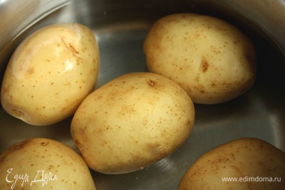 Картофель тщательно вымыть с щеткой, залить в кастрюле холодной водой, посолить, довести до кипения и варить 5–10 минут до готовности. Воду слить, картофель нарезать четвертинками или половинками.