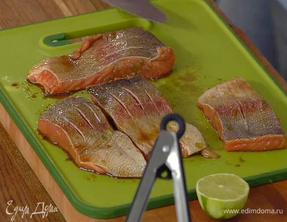 Форель поместить в маринад и дать постоять несколько минут, затем выложить рыбу на рабочую поверхность и сделать на коже неглубокие надрезы ножом.