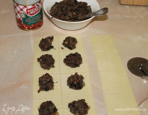 Раскатайте тесто в пласт тощиною 2–3 мм, нарежьте на квадраты со стороной 5 см. Положите на середину каждого квадратика начинку.