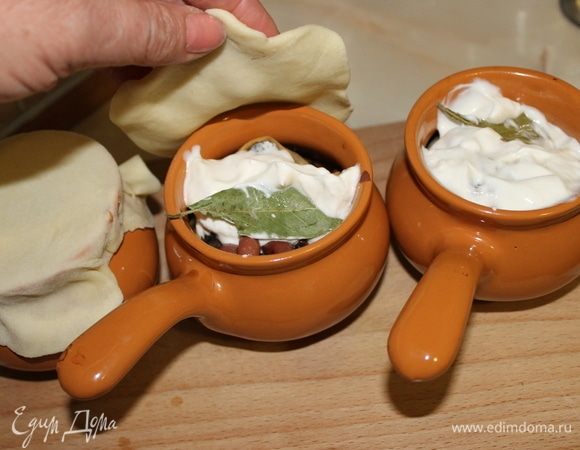 Добавьте в горшочки сметану, лавровый листик, из остатков теста сделайте крышку и верните кундюмы в духовку томиться на 15 минут.