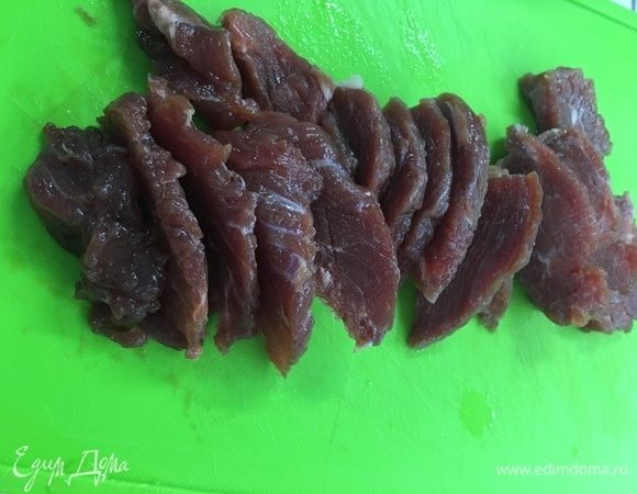 Подготовить мясо, промыть и нарезать на тонкие пластины.