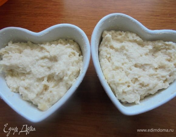 Керамические порционные формы смазать изнутри сливочным маслом и присыпать мукой, излишки муки встряхнуть. Выложить тесто в формочки.