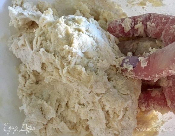 Сначала можно ложкой соединить все составляющие теста, но потом работаем руками. Ведь только руками можно почувствовать его консистенцию и понять, нужно ли добавить еще водички или подлить маслица. Сначала тесто, как на фото, хлопьями и липкое, но продолжаем месить.