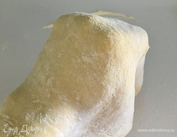 Затем подсунуть руки ладошками вниз под тесто, согнуть пальчики и тыльной стороной ладони, а также костяшками пальцев начать растягивать тесто от центра к периферии. Когда центр хорошо растянут, переходим к растяжке краев. Работаем пальчиками, аккуратно растягивая весь плат теста в тонкий слой.