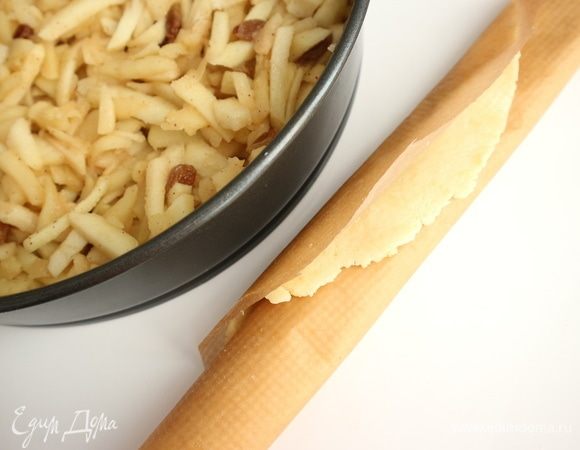 Положить равномерно остывшую начинку в форму. Для приготовления верхнего слоя понадобится бумага для выпечки. Положить тесто на бумагу, раскатать скалкой тонко в форме круга по размеру формы, накрыв сверху бумагой для выпечки. Снять верхний слой бумаги, нижний слой подрезать ножницами по размеру круга из теста + 1 см по окружности. Скатать тесто с бумагой трубочкой.