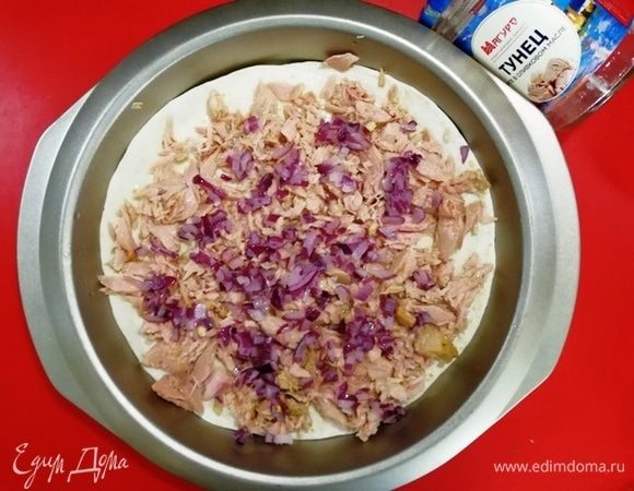 Тортильи выкладываем в форму для запекания. Сверху выкладываем разобранный тунец ТМ «Магуро» и красный лук, нарезанный мелким кубиком.