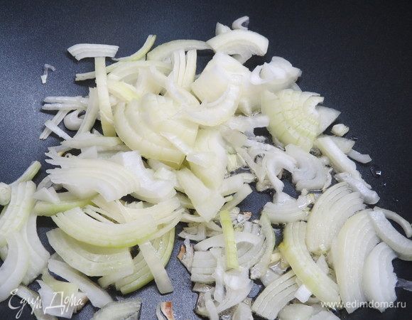 Репчатый лук нарезать полукольцами. В глубокой сковороде-воке нагреть оливковое масло, добавить нарезанный лук.