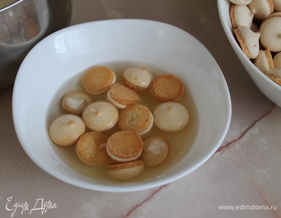 Собираем десерт. Десерт можно собирать в порционные креманки или в большую форму с высокими бортиками. Печенье по одному окунайте на секунду в ананасовый сироп и плотно одно к одному выложите на дно формы. Как на фотографии делать не стоит, так как печенье очень нежное, быстро впитывает сироп и размокает.