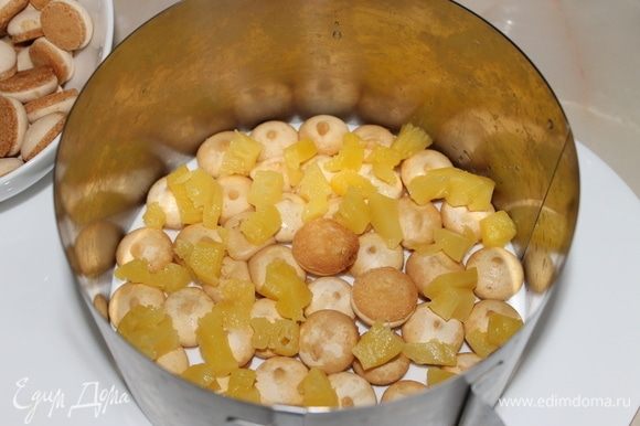 На печенье разложите кусочки ананасов и выложите часть сырного крема.