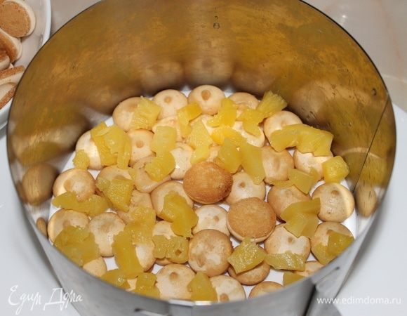 На печенье разложите кусочки ананасов и выложите часть сырного крема.