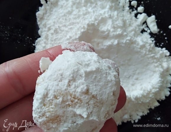 Духовку разогреть до 200°С. На тарелку насыпать сахарную пудру. Ложечкой набрать тесто, скатать шарик и хорошенько обвалять в пудре.