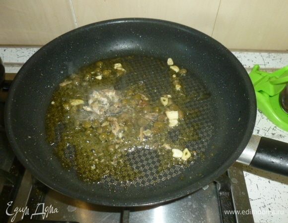 Спагетти отварить в подсоленной воде до состояния аль денте, откинуть на дуршлаг (сохранить немного воды от варки). В большой сковороде или сотейнике разогреть масло, пропустить через пресс чеснок, добавить анчоусы и каперсы.