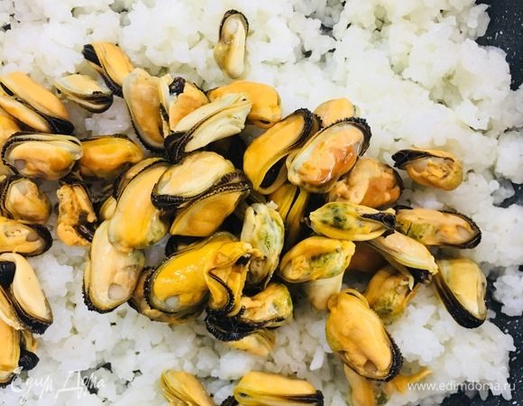 Разогреть сковороду, налить масло, выложить отварной рис, мидии и немного прогреть.