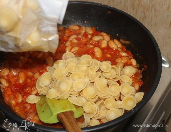 Следующим шагом добавьте в соус подготовленную пасту. Влейте куриный бульон или просто горячую воду. Перемешайте пасту с соусом, посолите и, накрыв крышкой сотейник, готовьте ее до состояния аль денте.