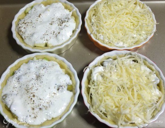 Поверх овощей выкладываем примерно по две столовые ложки заливки, перчим и посыпаем тертым сыром.