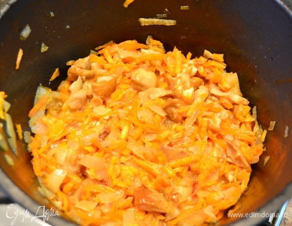 Затем добавляем натертую морковь и размороженные белые грибы, обжариваем до готовности. Выложить в тарелку, добавить чеснок, зелень.