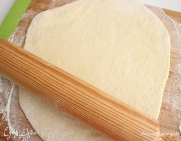 Достать для раскатки кусочек теста (третью часть или половину), остальное тесто снова замотать в пленку, чтобы оно не пересохло. Раскатать скалкой на присыпанной мукой поверхности.