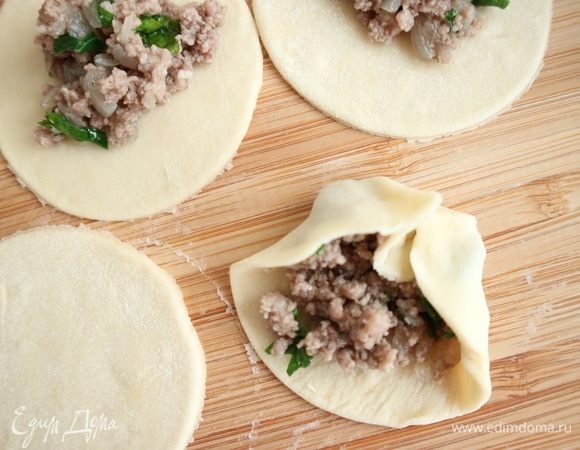 Затем справа немного натянуть небольшой кусочек теста с краю на противоположную сторону, затем то же самое проделать с противоположной стороны. Края теста идут внахлест с противоположной стороной. И так далее, делая загибы то с одной, то с другой стороны. У меня на столе во время этого процесса стоит мисочка с небольшим количеством муки, куда я периодически во время лепки обмакиваю пальцы.