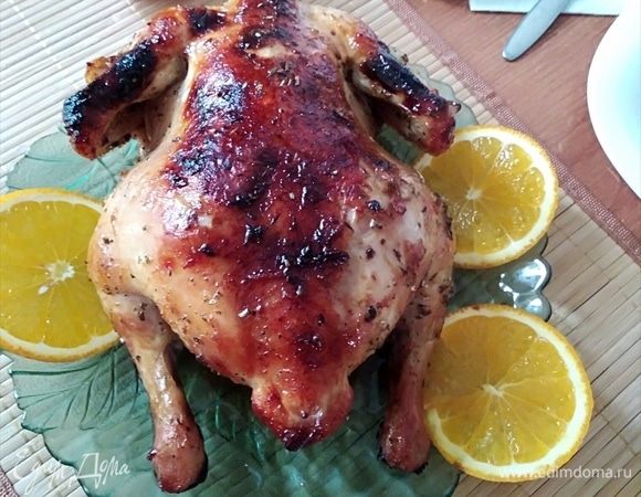 Духовку разогреть до 200°C. В смазанную маслом форму для запекания уложить курочку, полить маринадом и поставить в духовку. Когда подрумянится, перевернуть. Можно прикрыть фольгой те части курочки, которые быстрее зажарились. Оставить отдохнуть на 10 минут и можно подавать, украсив апельсином. Приятного аппетита!